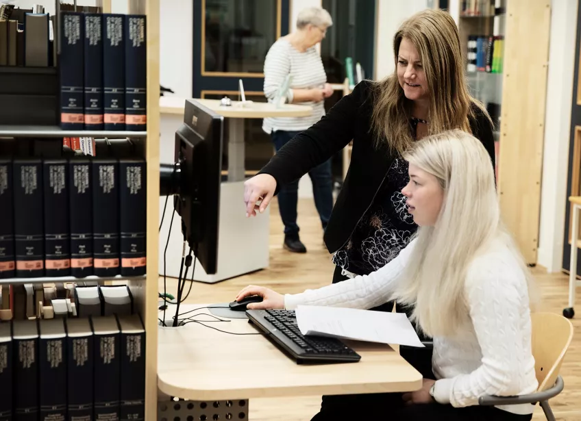 Två personer framför en dator på ett bibliotek. Foto: Johan Bävman.